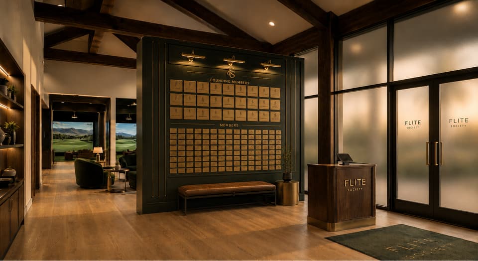 The club entry: a two-tier wall of brass nameplates — founding members above, members below — beside the check-in desk.